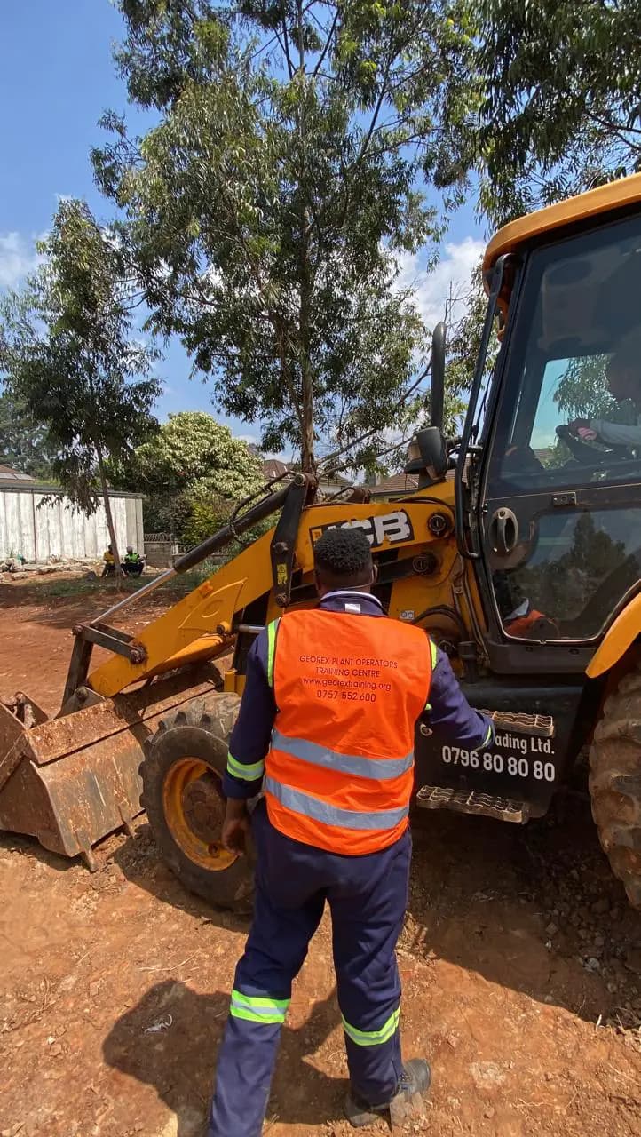 Trainee completing a walkaround inspection of a JCB backhoe loader