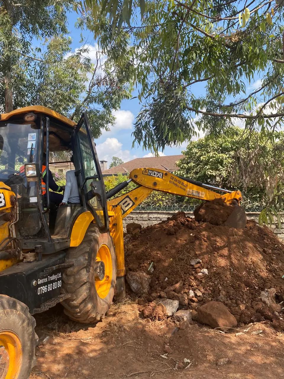 Student operating the rear excavator arm of a JCB backhoe loader