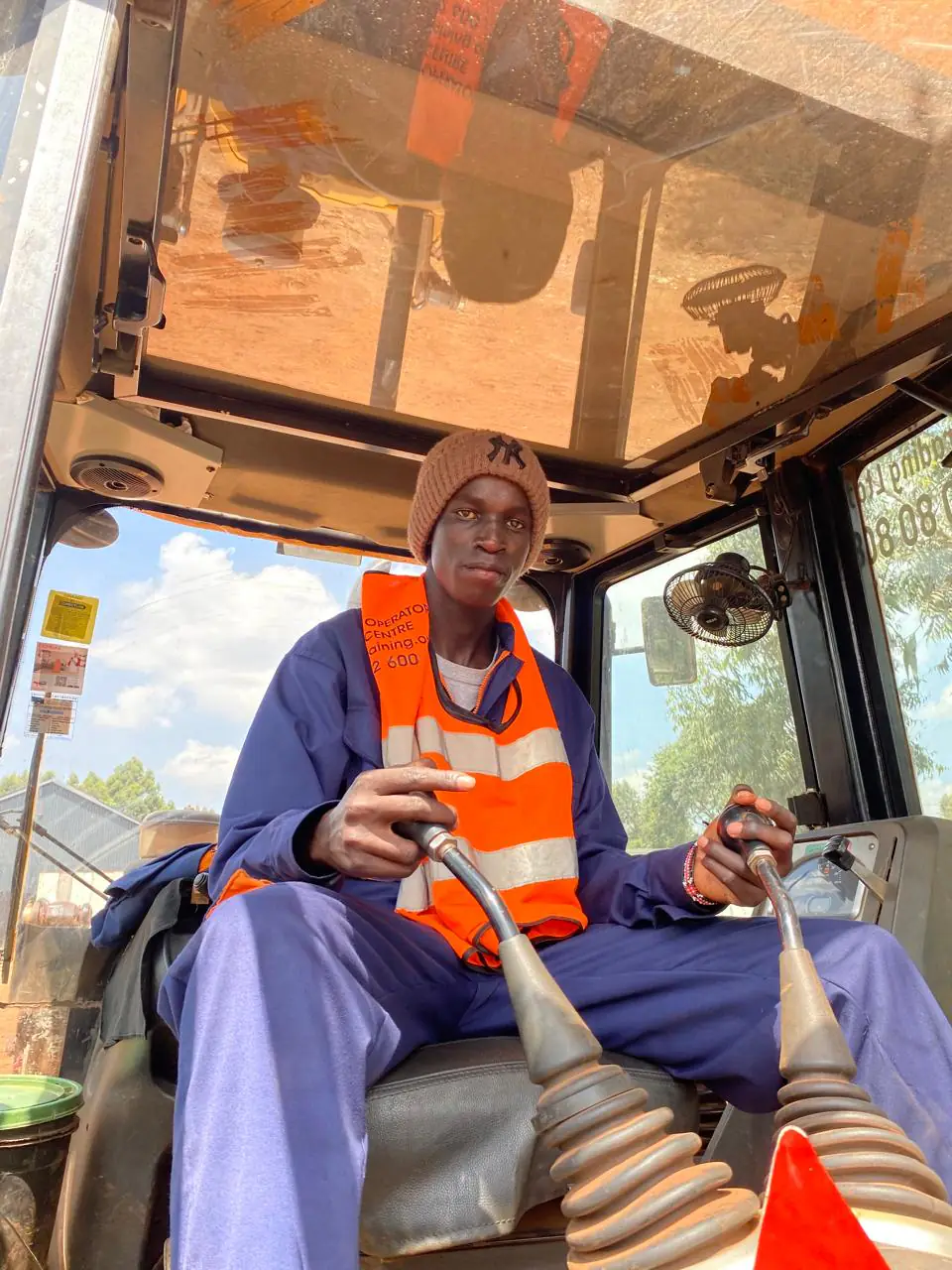 Student practising the twin backhoe control levers inside the operator cab